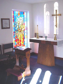 Sun shining through chapel stained glass window on altar